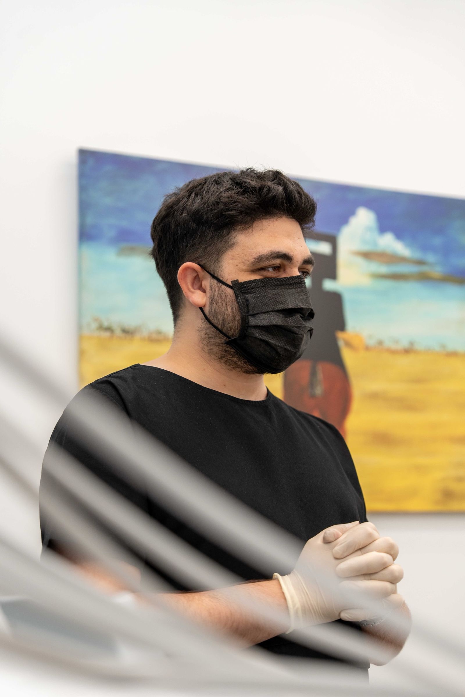 A dentist in black scrubs standing in a treatment room.