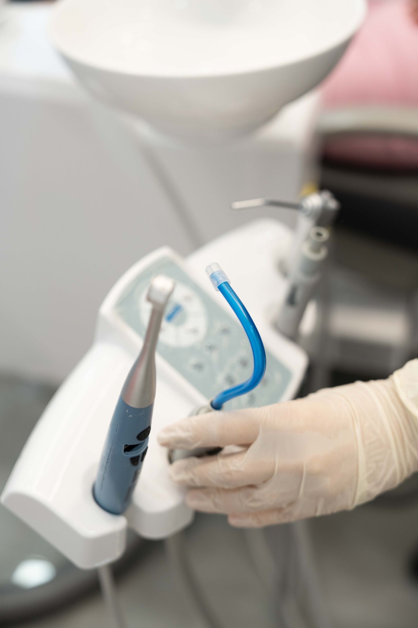 A handheld intraoral scanner in a gloved hand.