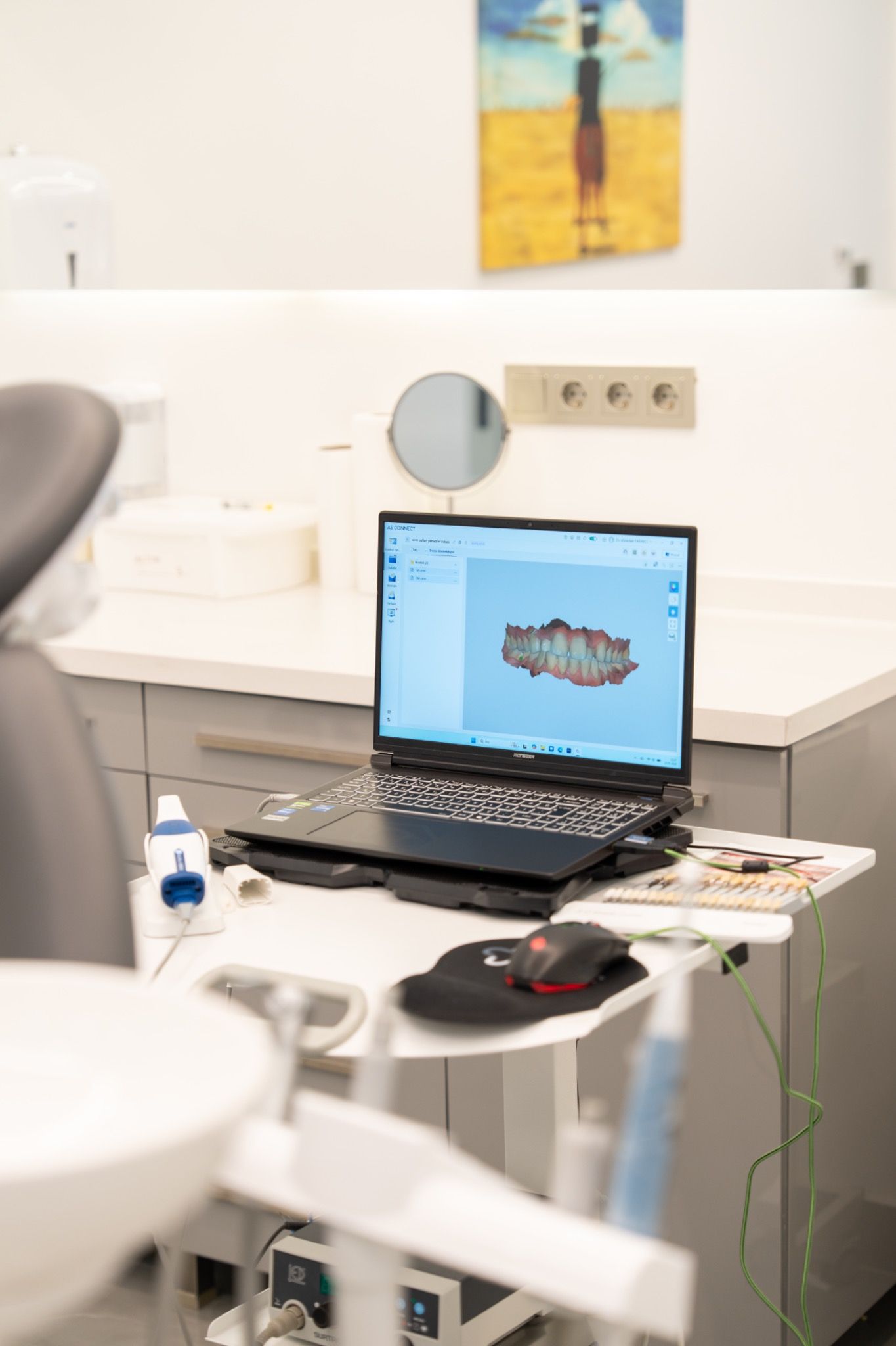 A laptop on a mobile workstation beside a treatment chair.